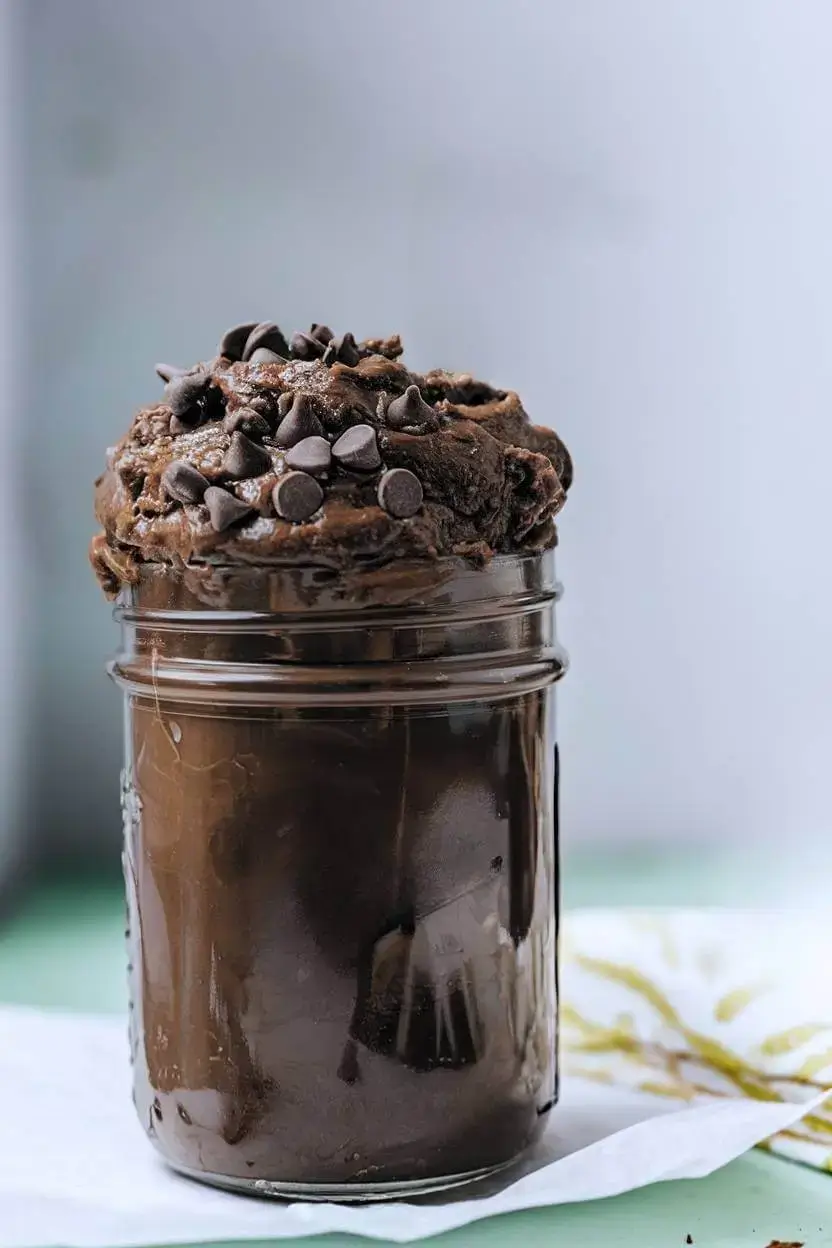 Edible brownie batter in a glass jar topped with chocolate chips.