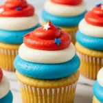 4th of July cupcakes placed on a white marble surface, topped with blue, white and red frosting swirls.