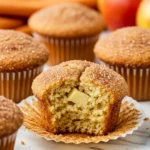 Apple cinnamon muffins on a white marble surface.