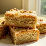Banana bread brownies on a white plate against a light-yellow surface.