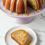 Banana bundt cake on a light purple cake stand and a slice of it on a white plate next to it.