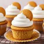 Banana pudding cupcakes placed on a cooling rack against a light pink surface.