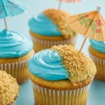Beach cupcakes placed on a light blue surface.