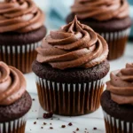 Chocolate cupcakes placed on a white marble surface.