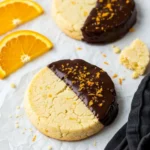 Two chocolate orange shortbread cookies on a piece of parchment.