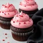 Chocolate strawberry cupcakes on a light gray surface and a black napkin beside.