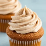 Two churro cupcakes placed on a light blue surface.