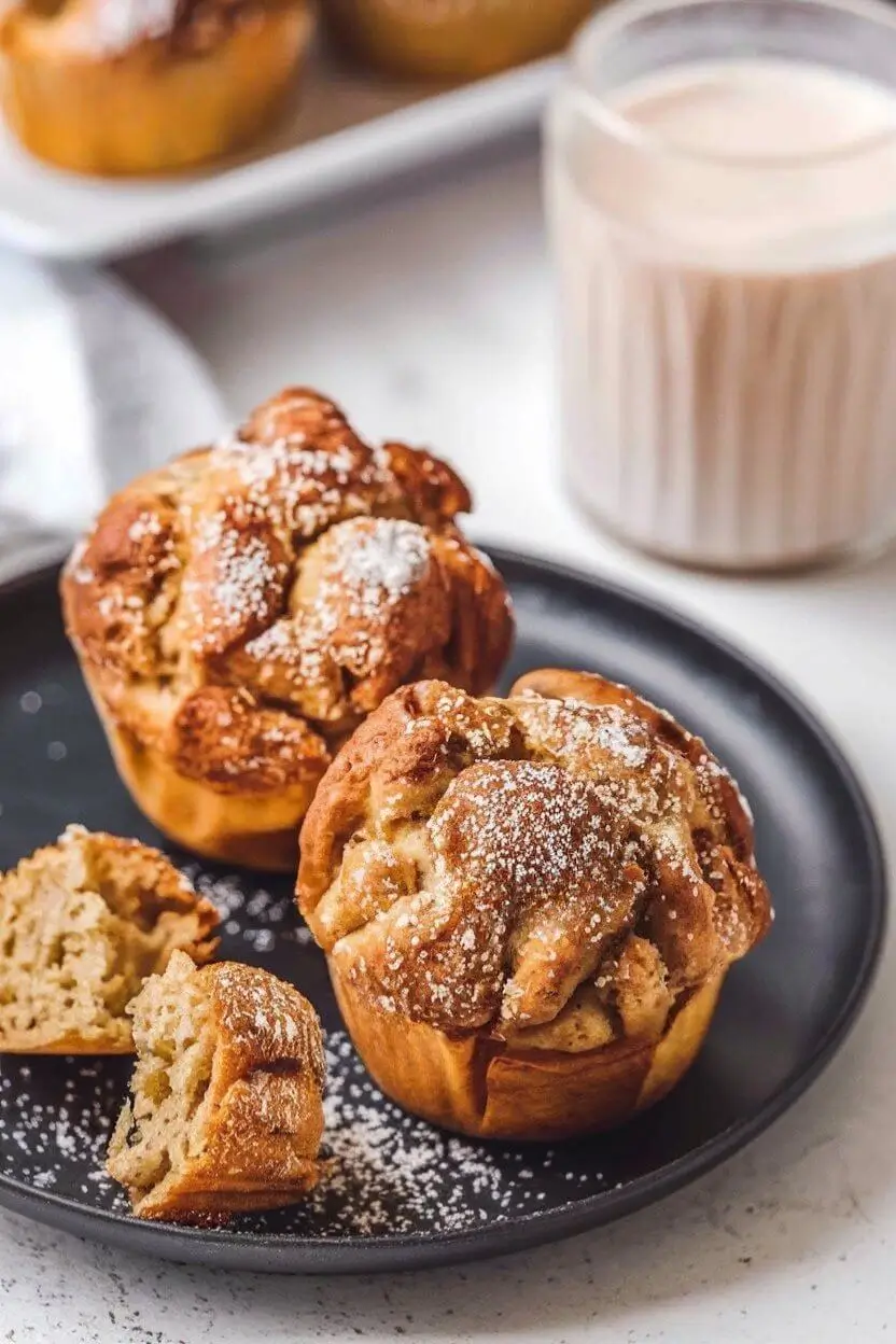 Cinnamon Sugar French Toast Muffins on a black plate with powdered sugar on top.