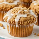 Coffee cake muffins on a white plate against a white marble surface.
