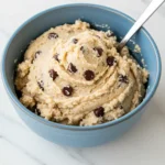 Cottage cheese cookie dough in a blue ceramic bowl against a white marble surface.