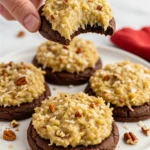 German chocolate cookies on a white plate and a hand holding a cookie with a bite taken out of it.