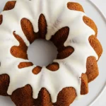 Gingerbread bundt cake on a big white plate drizzled with maple glaze.