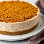 Gingerbread cheesecake on a big white plate and a brown napkin next to it.