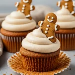 Gingerbread cupcakes topped with cream cheese frosting and garnished with gingerbread cookies.