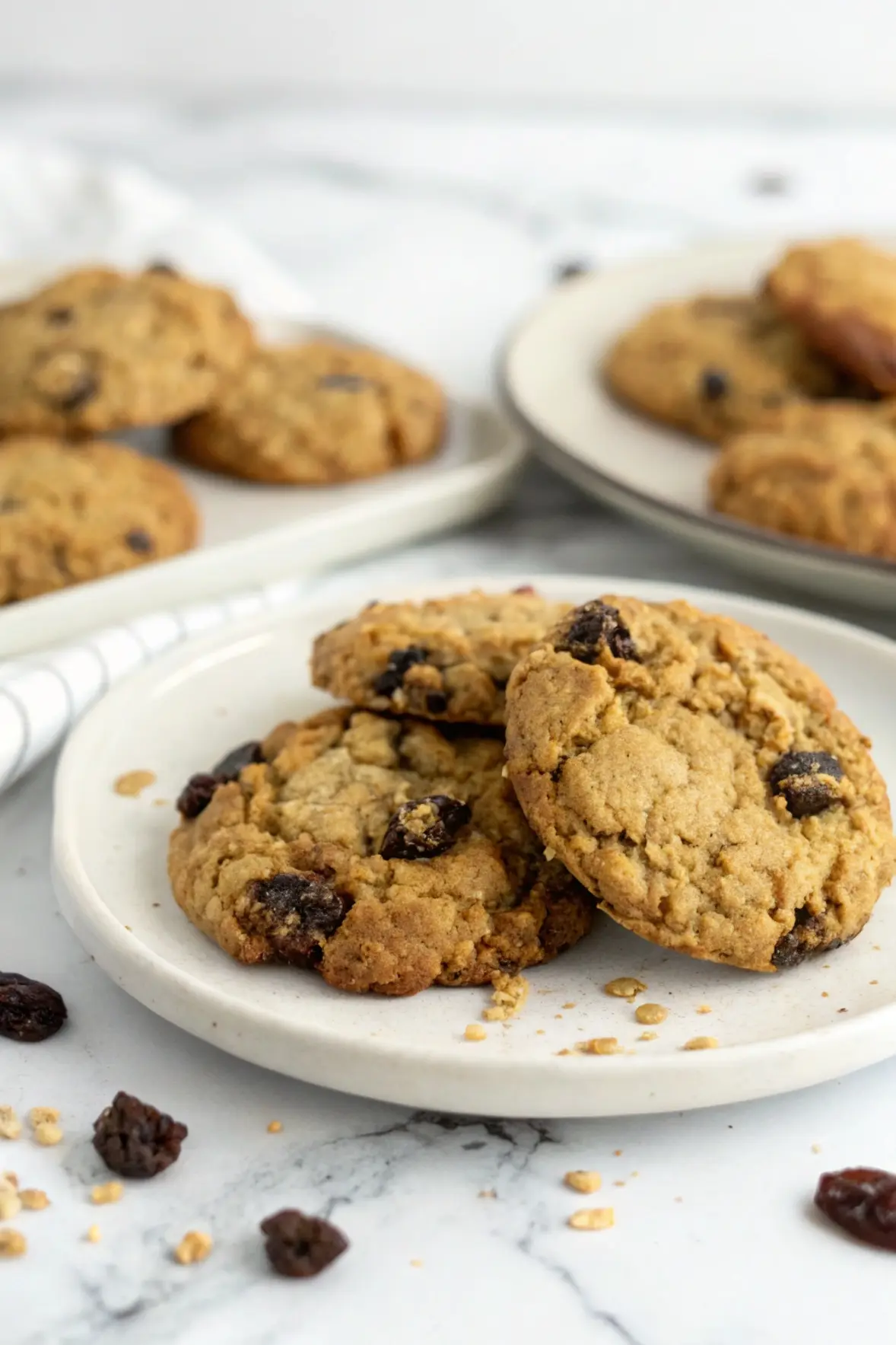 Gluten-Free Oatmeal Raisin Cookies on a white plate against a white marble surface.