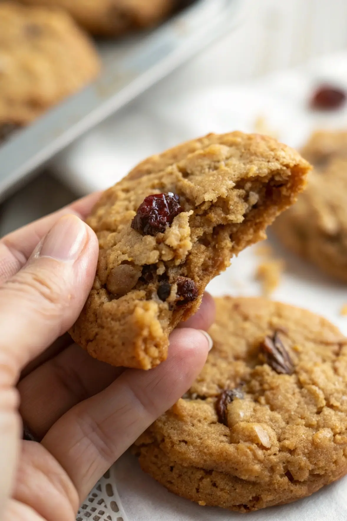 A hand is holding one Cookie with a bite taken out of it.