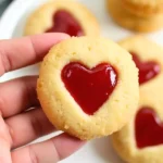 A hand holding a Heart Jam Thumbprint Cookie.