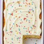 Funfetti cake on a white baking pan with a slice missing.