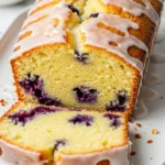 Lemon Blueberry Pound Cake on a white plate drizzled with lemon glaze.