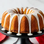 Lemon bundt cake on a black cake stand with lemon glaze on top.