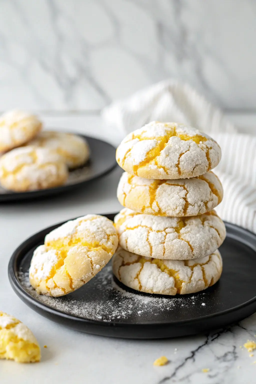 Stack of lemon crinkle cookies on a black plate.
