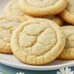 Lemon sugar cookies on a white plate and some Marguerite's around the plate.