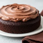 Mini chocolate cake on a white plate and a brown napkin next to it.
