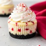 Mini peppermint cheesecakes on a gray surface and a red napkin beside.