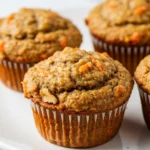 Morning glory muffins on a white plate against a white marble surface.