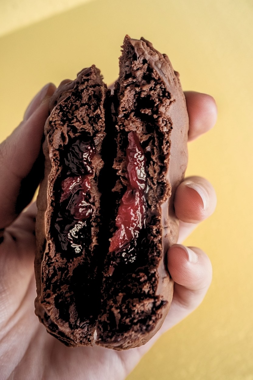 One orange chocolate cookie serbian split in half, showing the plum jam inside.