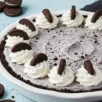 Oreo pie in a white pie dish against a light blue surface.