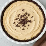 Peanut butter pie in a white pie dish and a brown napkin around.