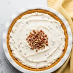 Pecan cream pie on a white pie dish.