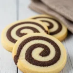 Three pinwheel cookies on a white wood surface.