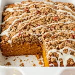 Pumpkin coffee cake in a white pan with a slice missing from it.