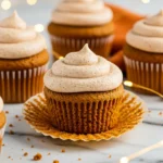 Pumpkin cupcakes on a white marble surface with led string glowing around.