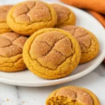 Pumpkin snickerdoodle cookies on a white plate against a white marble surface.