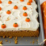 Pumpkin spice cake on a gray baking pan placed on a white marble surface, and a few led strings glow beside it.