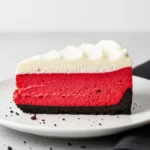 A slice of red velvet cheesecake on a white plate.