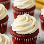 Red velvet cupcakes placed on a white marble surface.