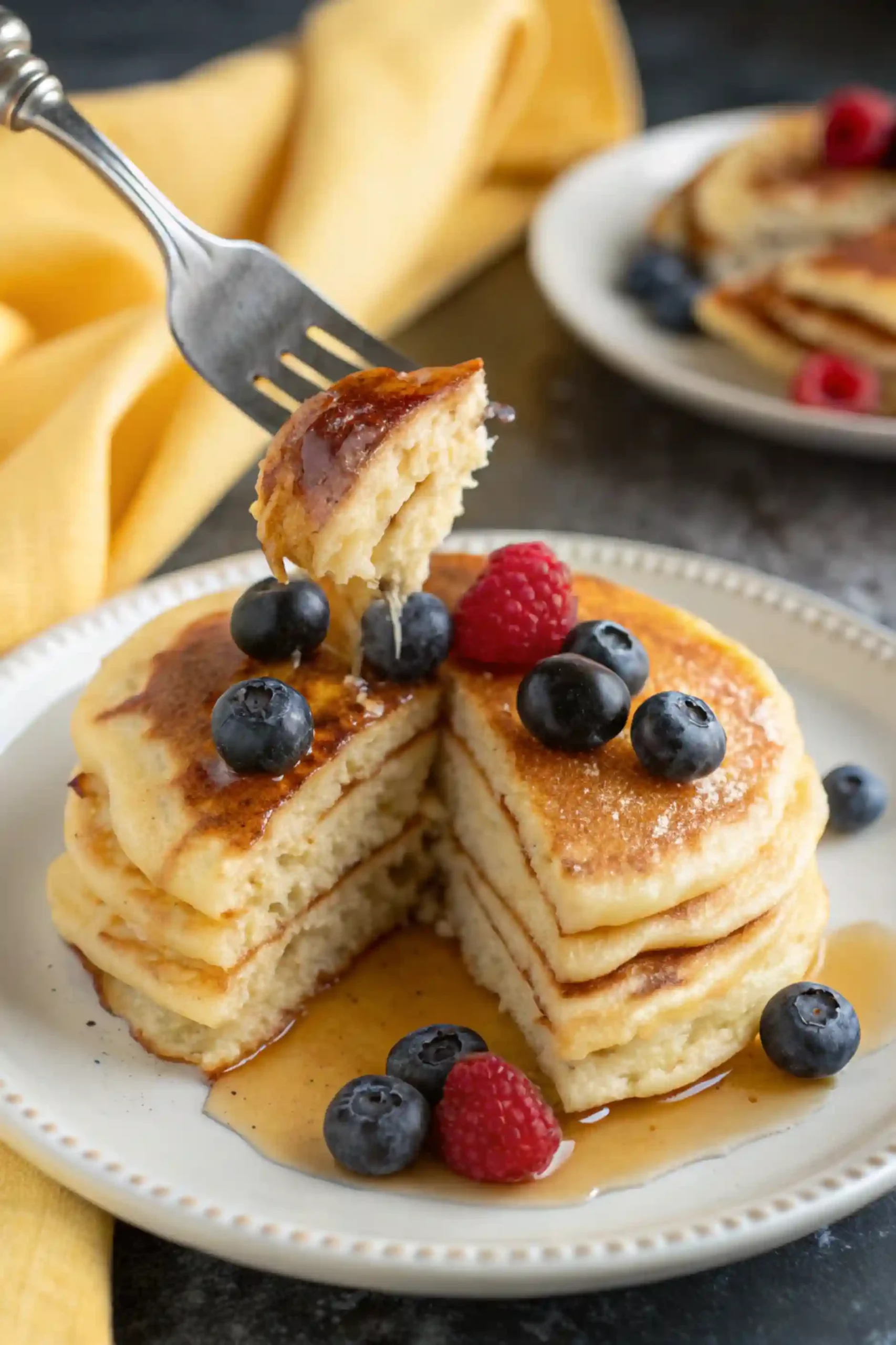 Sourdough discard pancakes on a white plate and a serving taken out of it.