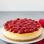 Strawberry cheesecake on a white plate and a red napkin beside it.