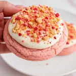 A hand holding one strawberry crunch cookie.