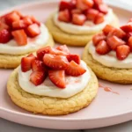 Strawberry shortcake cookies on a light pink plate.