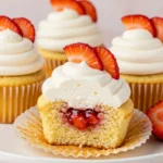 Strawberry shortcake cupcakes on a white plate and one of them split into half.