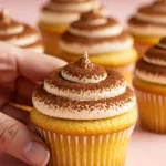 Tiramisu cupcakes placed on a light pink surface.