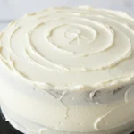 White velvet cake on a black cake stand.