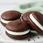 Whoopie pies on a white plate against a marble surface.