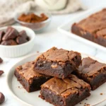 Almond flour date brownies on a white plate against a white marble surface.