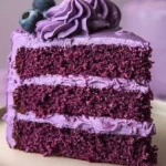 Slice of purple velvet cake recipe placed on a white plate.